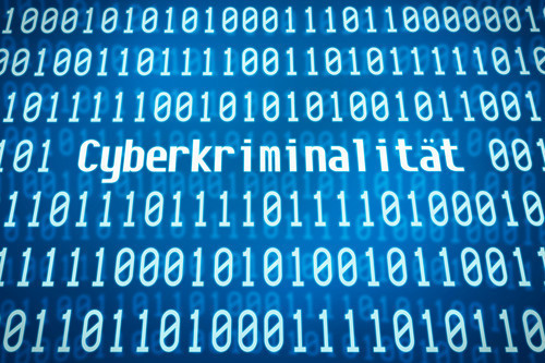 Weißer Binärcode auf blauem Hintergrund mit dem eingeflochtenem Wort "Cyberkriminalität"